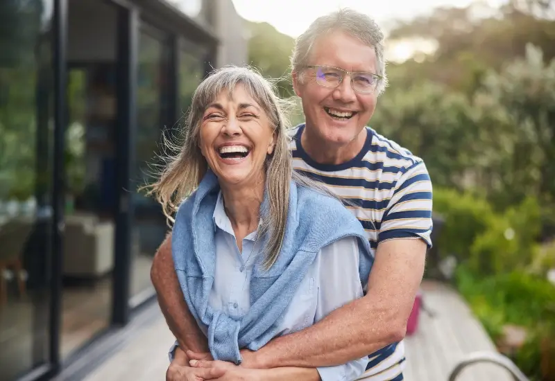Mature couple standing arm in arm and laughing