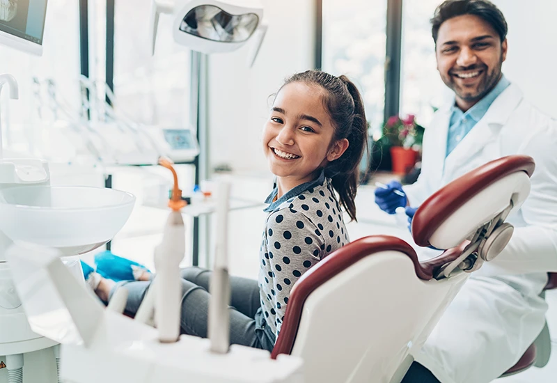 Little girl in a dentist chair smiling before a tooth extraction procedure in Atlanta